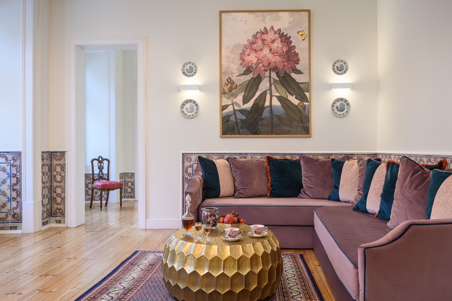 Living room with a purple couch, gold coffee table, artwork, and decorative wall tiles.