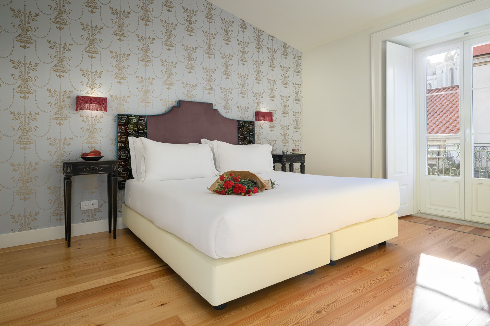 Bedroom with large bed, decorative wallpaper, two and a doorway to a balcony in an Arc Classic one-bedroom apartment.