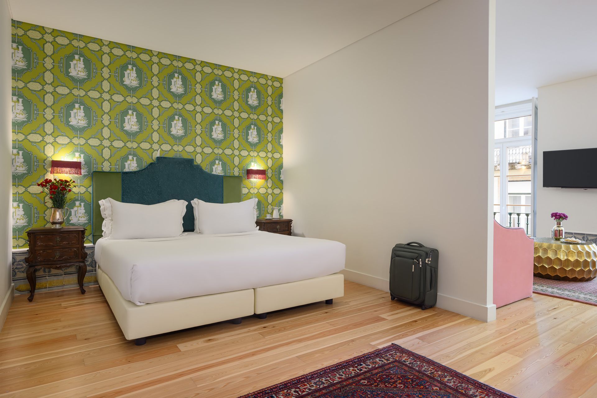 Hotel bedroom with a green patterned wall, double bed, and luggage.