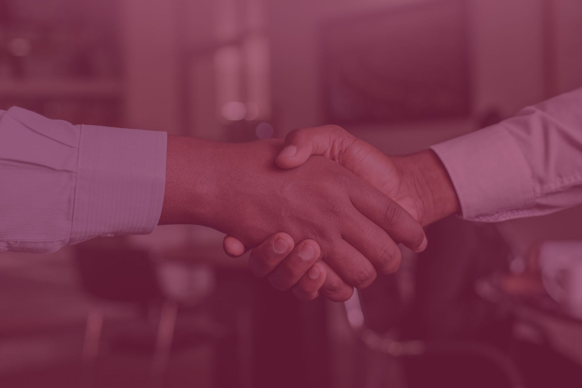Dos personas con camisas de negocios se dan la mano, en un espacio interior con una superposición roja.