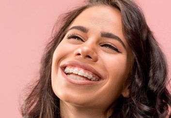 Una mujer con aparatos dentales está sonriendo.