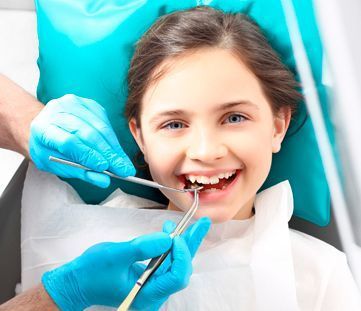 A una niña le están examinando los dientes un dentista.
