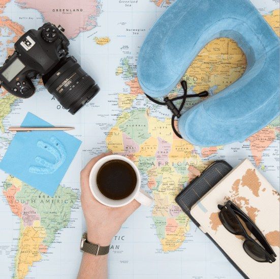 Una persona sostiene una taza de café frente a un mapa del mundo.