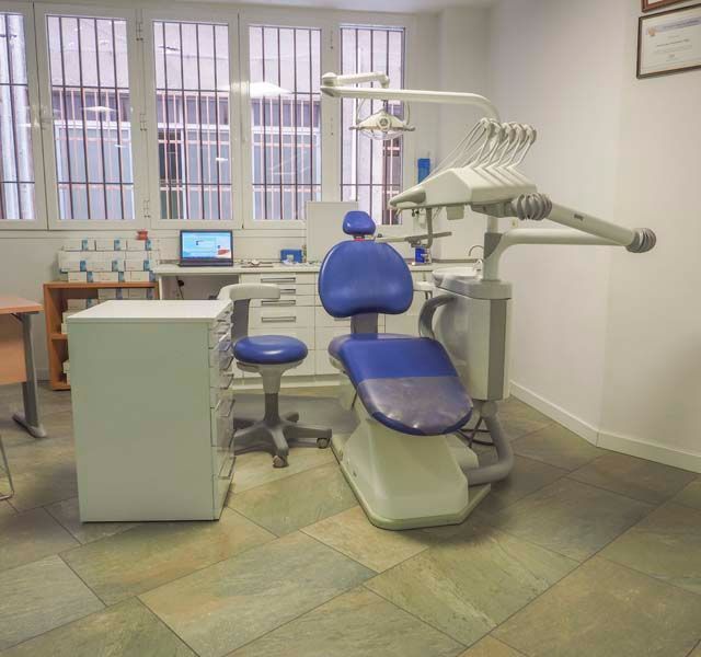 Un consultorio dental con una silla azul y una computadora portátil.