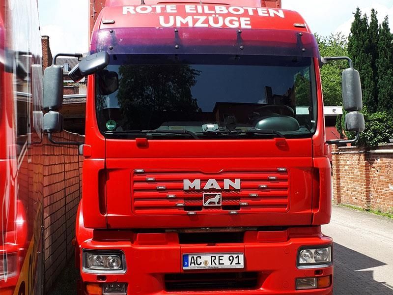 Ein roter LKW steht vor einer Backsteinmauer