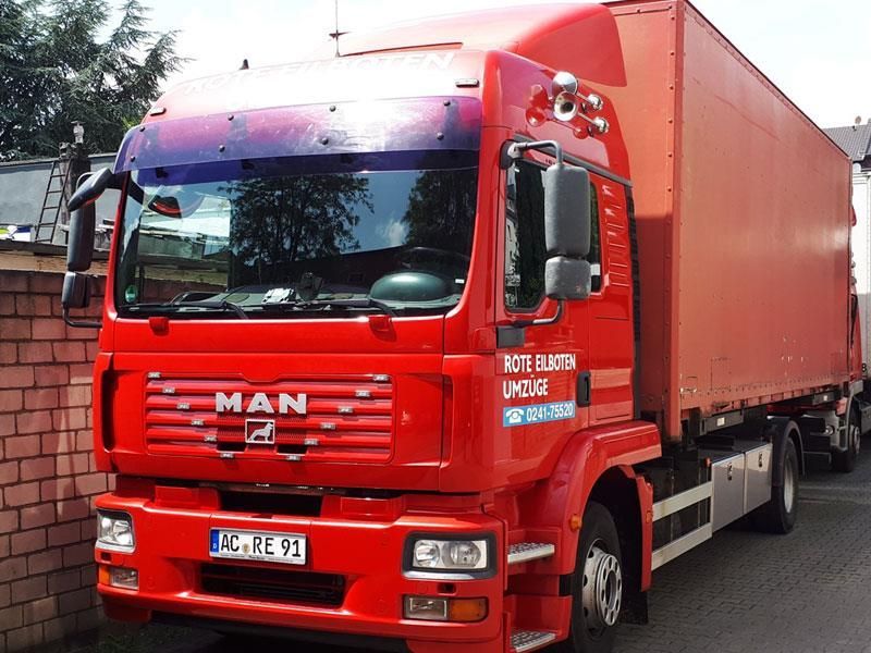 Ein roter LKW steht vor einer Mauer