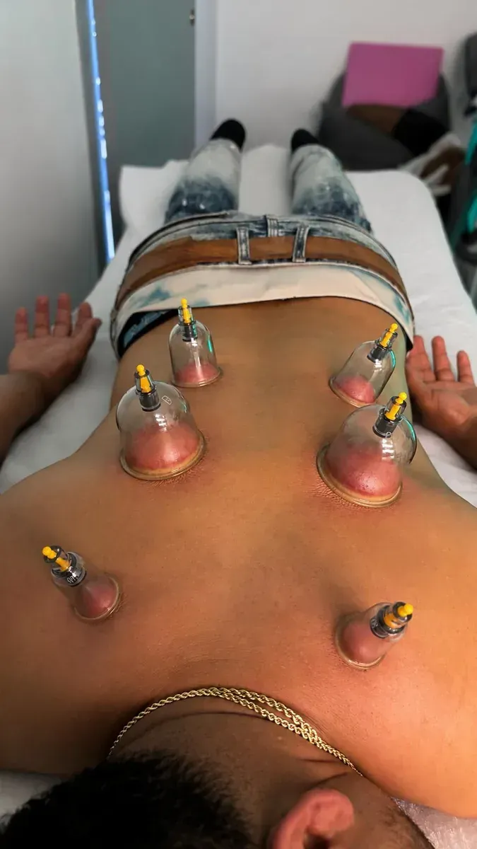 Manos masajeando la parte superior de la espalda y el cuello de una persona en una camilla de masaje.