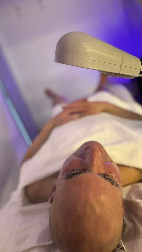 Persona recibiendo un tratamiento facial con un dispositivo portátil para el cuidado de la piel en un entorno de spa.