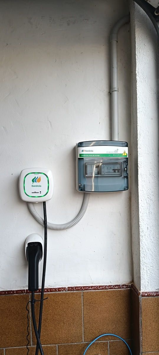 Inversor de panel solar y sistema de baterías montados en una pared blanca. Los cables rojos conectan los componentes.