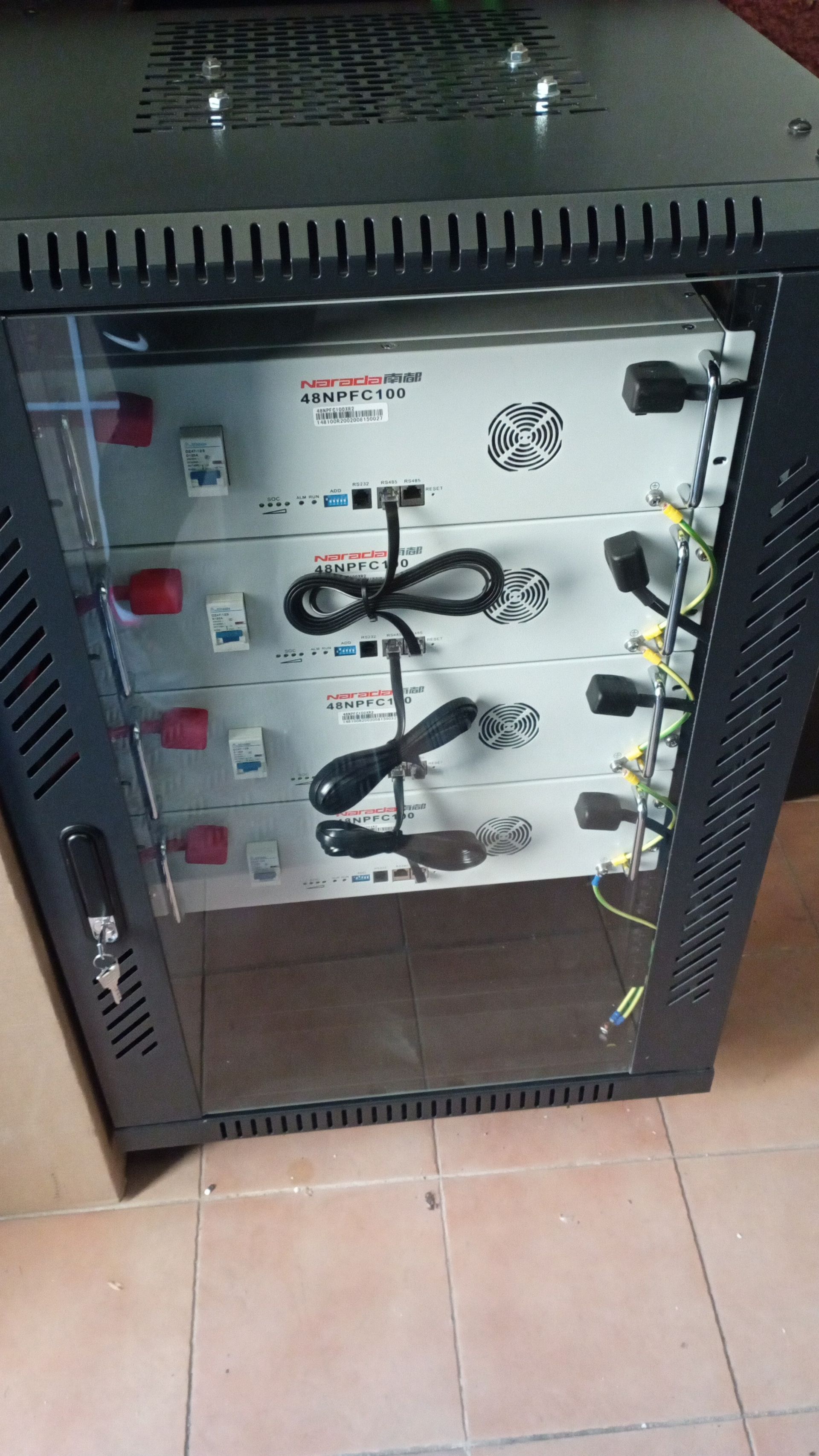 Paneles solares sobre un techo de tejas de terracota contra un cielo azul claro, parte de un edificio en un barrio.