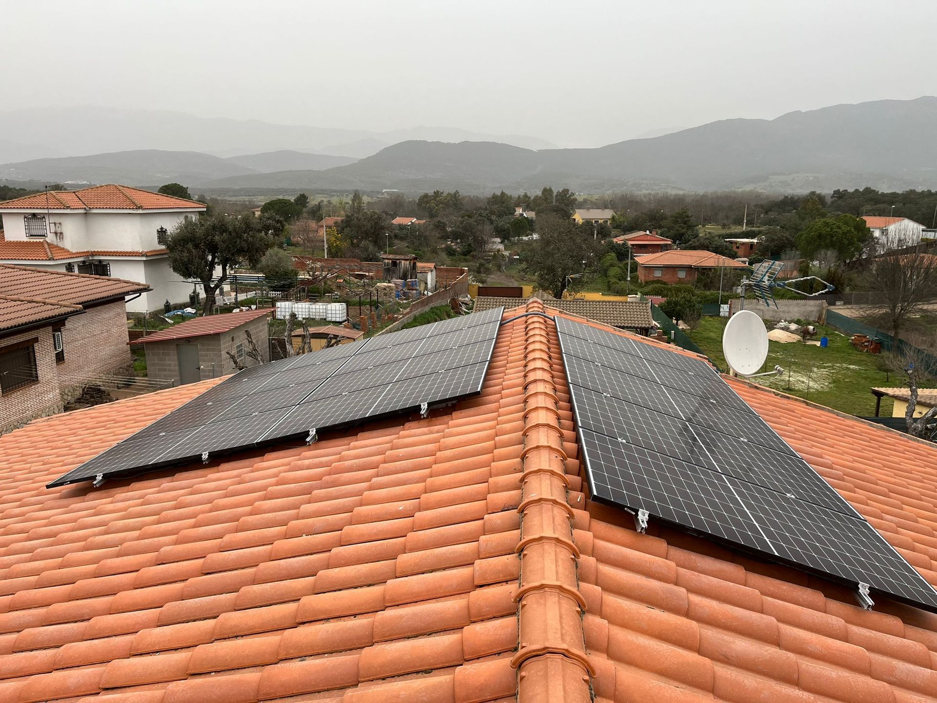 Paneles solares instalados en un techo de tejas rojas en un entorno al aire libre.