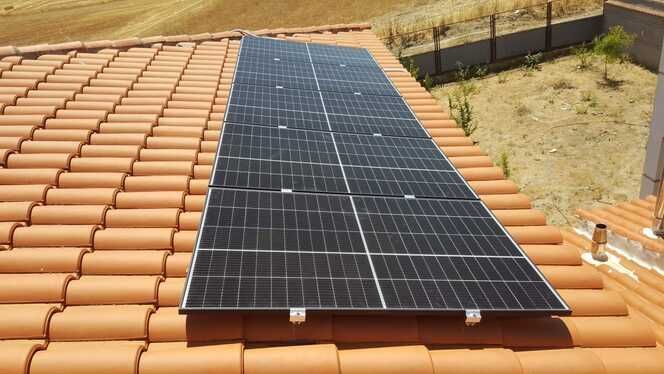 Paneles solares sobre un techo de tejas de terracota, captando la luz solar.