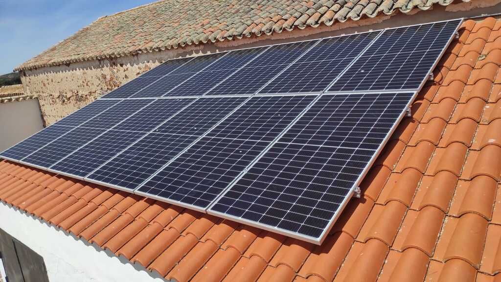 Paneles solares instalados en un techo de tejas de terracota, inclinados hacia el sol.