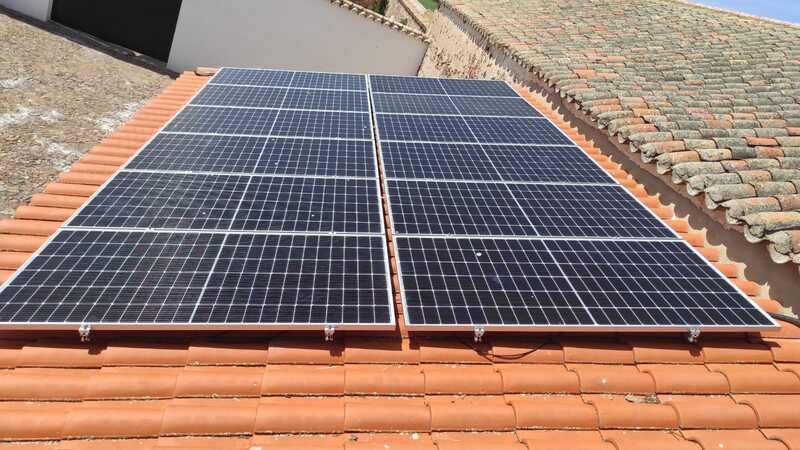Paneles solares sobre un tejado de tejas de terracota.