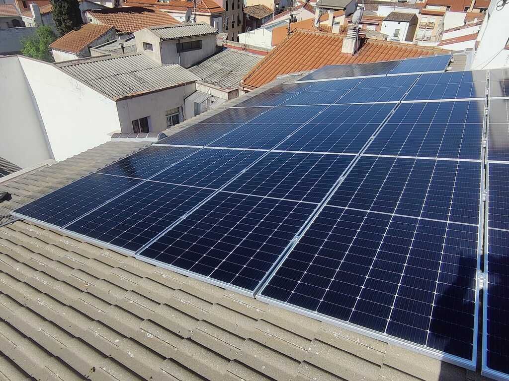 Paneles solares instalados en un techo de tejas, captando la luz solar en un barrio residencial.
