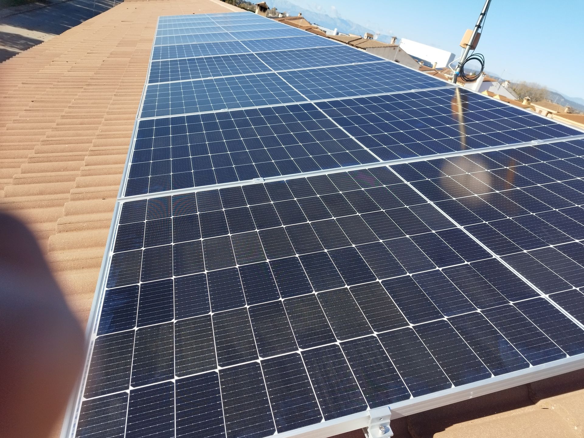 Paneles solares instalados en un techo de tejas de arcilla, captando la luz solar para obtener energía.