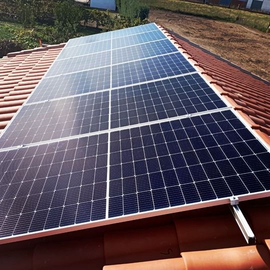Paneles solares instalados en un techo de tejas rojas, captando la luz solar.
