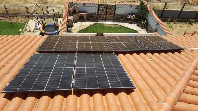 Paneles solares sobre un techo de tejas de terracota, con vista a un patio trasero.