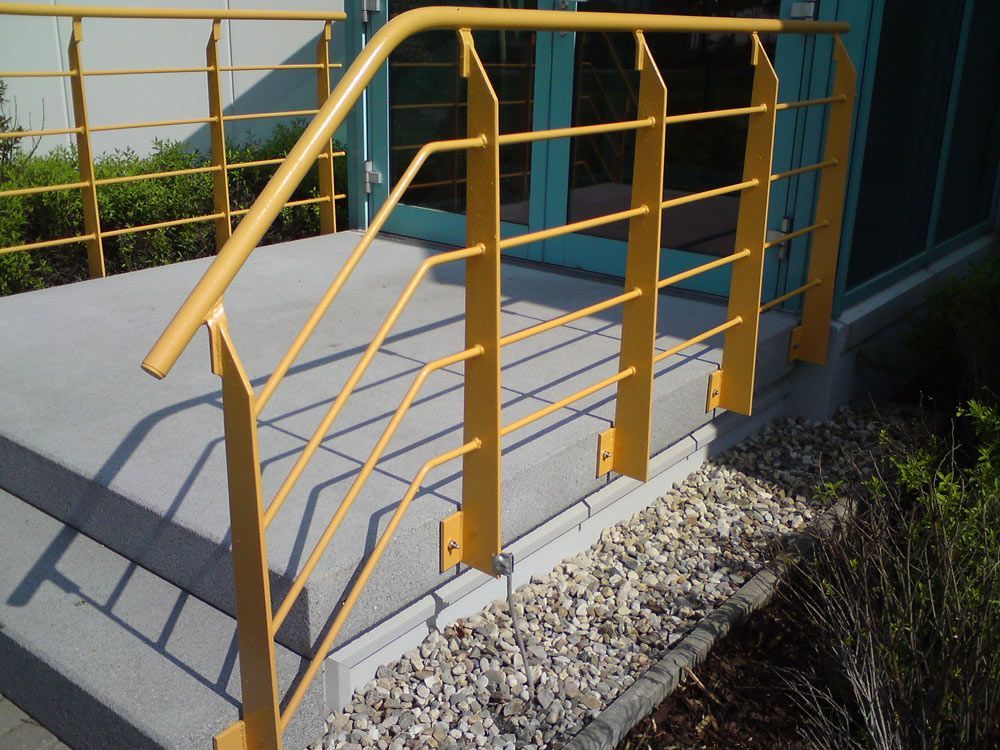 Ein gelbes Geländer an einer Treppe vor einem Gebäude