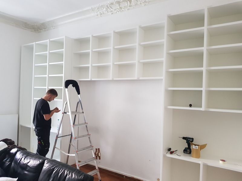 Ein Mann steht auf einer Leiter in einem Wohnzimmer.