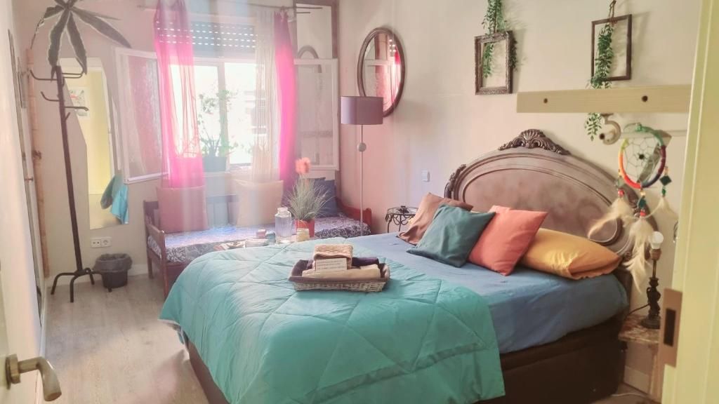 Habitación acogedora con colcha color turquesa, cortinas rosas, decoración en la pared 