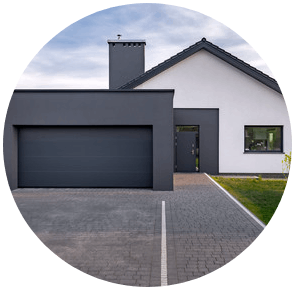Maison grise moderne avec un grand garage, une allée à l'avant et une petite pelouse.