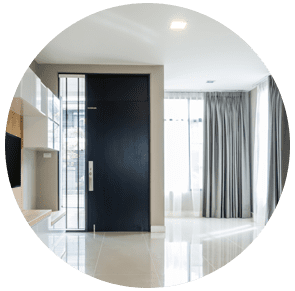 Intérieur d'un appartement moderne avec porte d'entrée noire, sol blanc brillant et rideaux gris près d'une fenêtre.