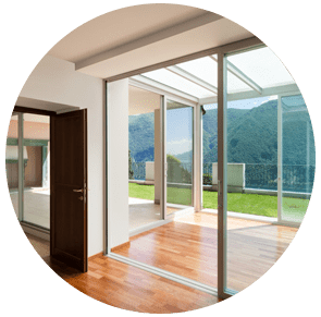 Chambre moderne et lumineuse avec portes coulissantes en verre donnant sur une terrasse en bois et vue sur les montagnes verdoyantes