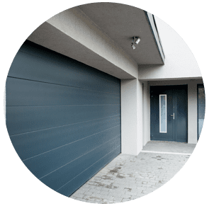 Entrée d'une maison moderne avec une grande porte de garage bleue et une porte d'entrée foncée sous un auvent couvert.