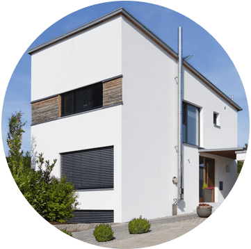 Maison moderne blanche de deux étages avec des volets foncés et une petite entrée sous un ciel bleu