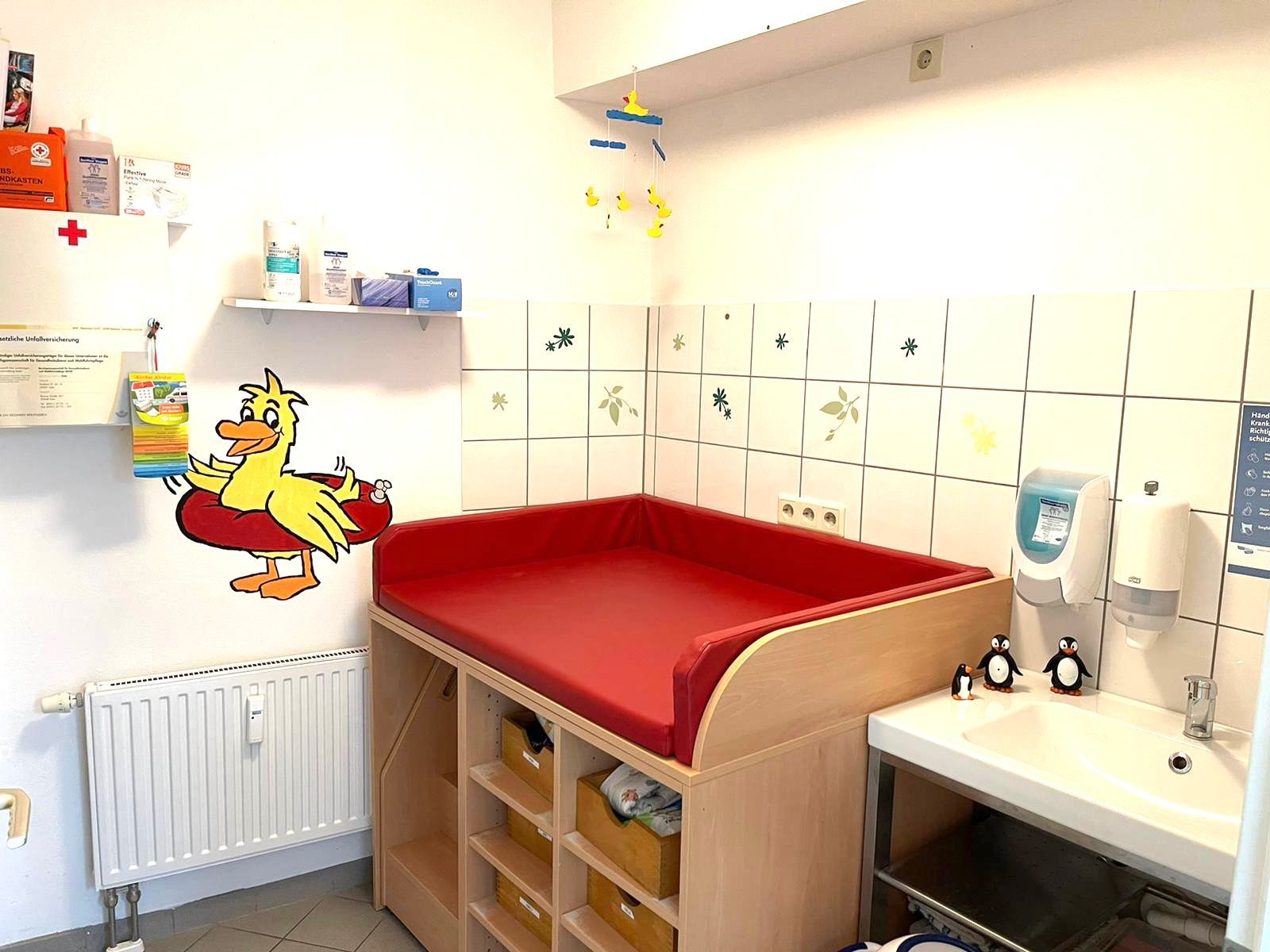 Ein Zimmer mit einem Wickeltisch und einem Bild einer Ente an der Wand.