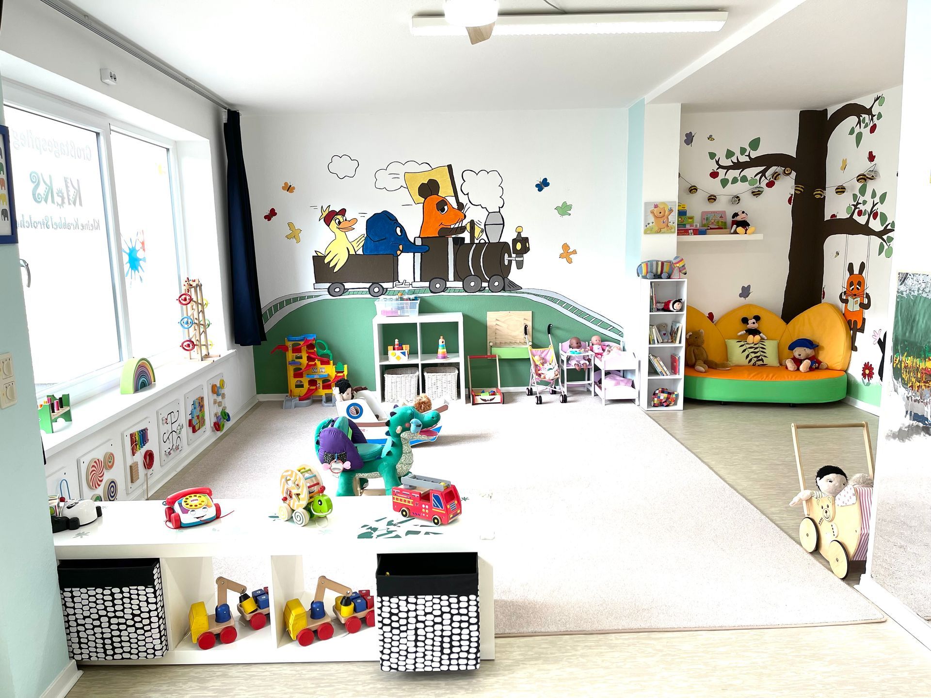 Ein großer Raum voller Spielsachen und einem Wandgemälde an der Wand.