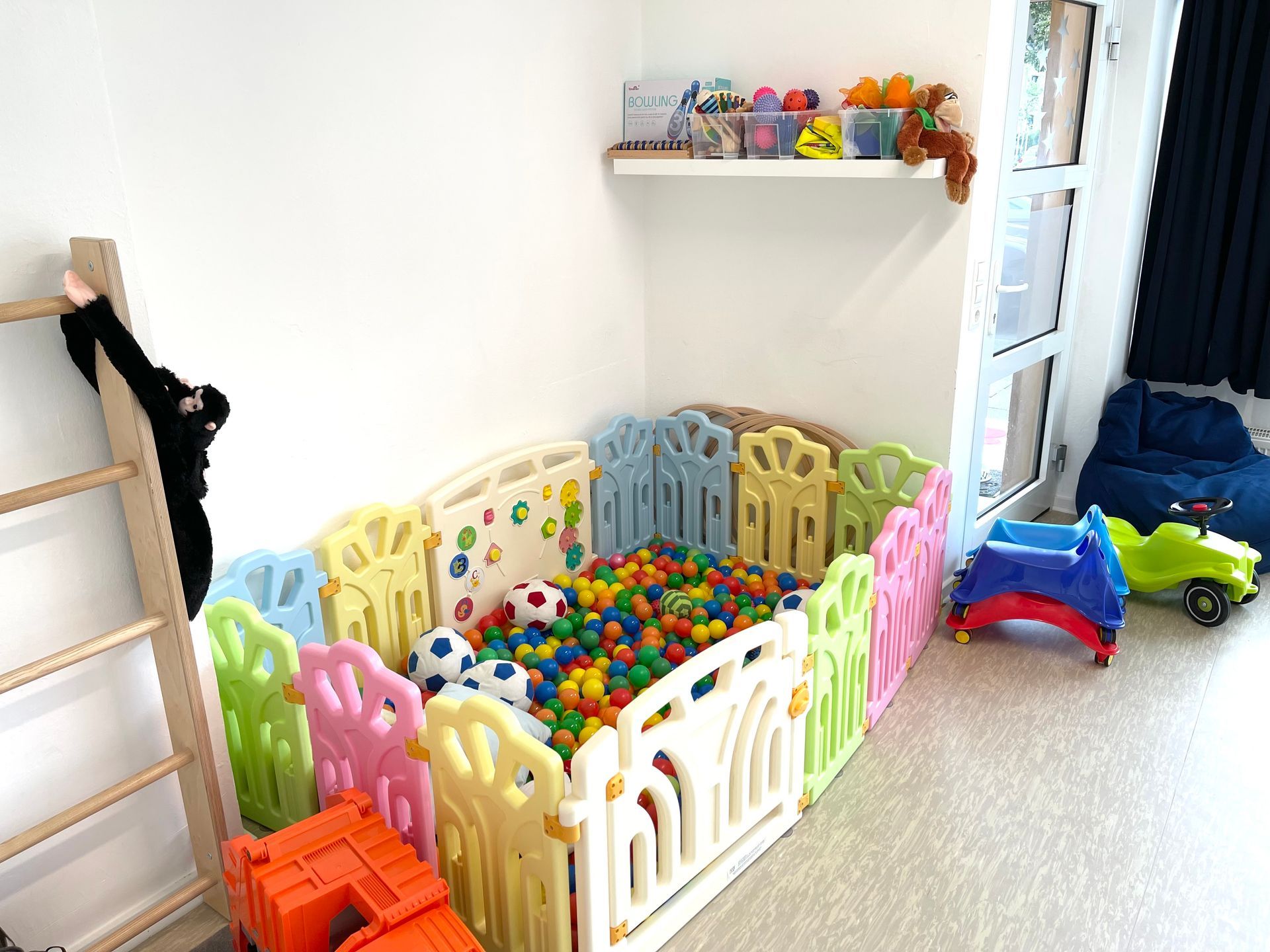 Ein Raum mit einem Zaun voller bunter Bälle und Spielsachen.