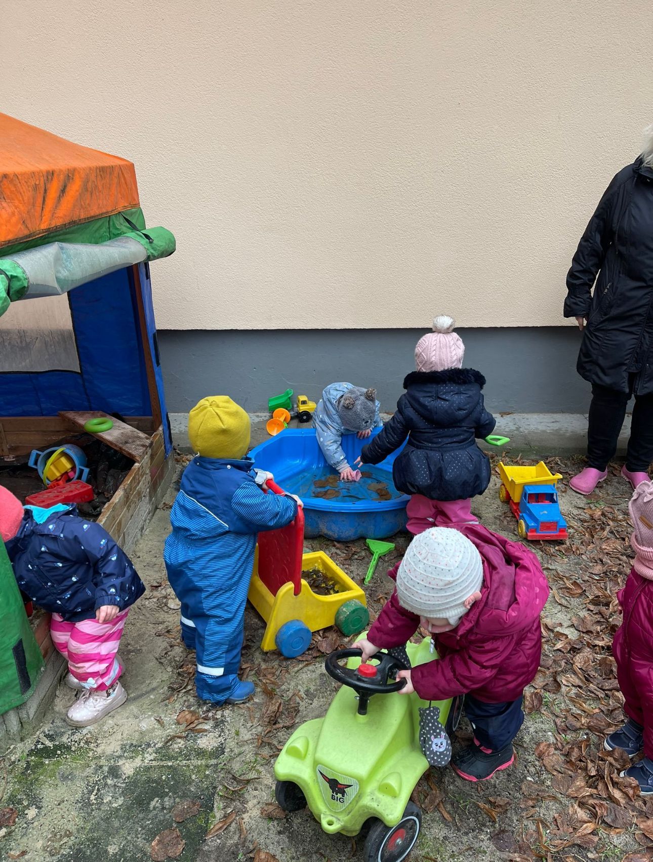 Eine Gruppe Kinder spielt in einem Sandkasten.
