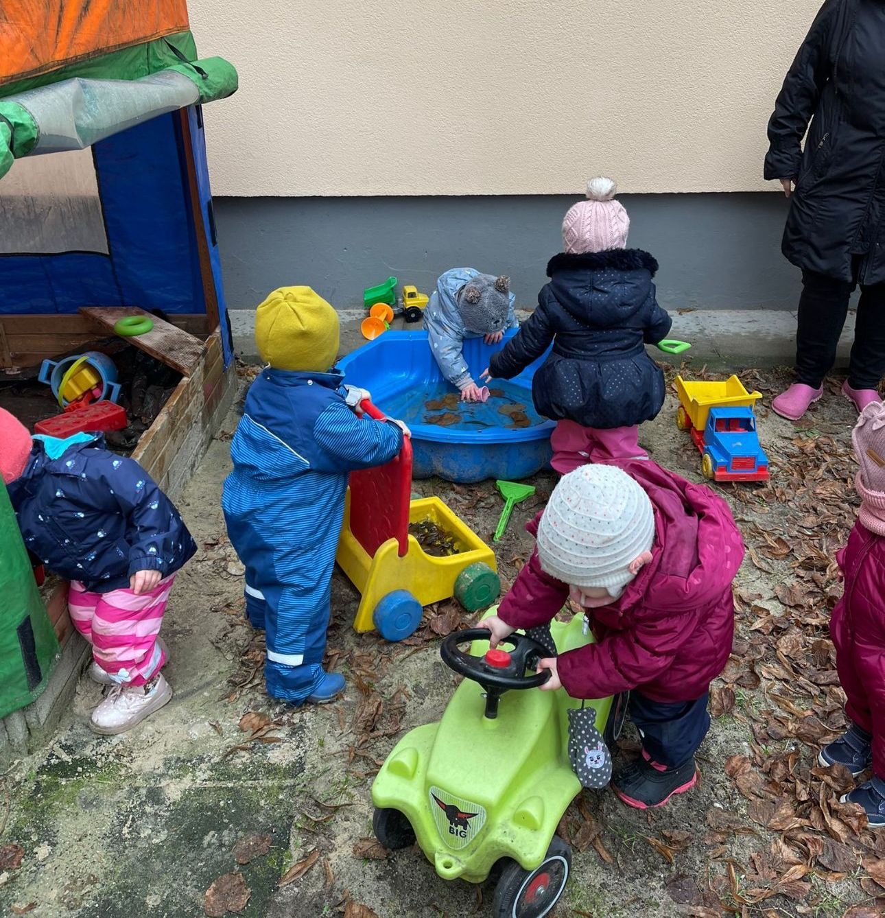 Eine Gruppe von Kindern spielt mit Spielzeug in einem Sandkasten