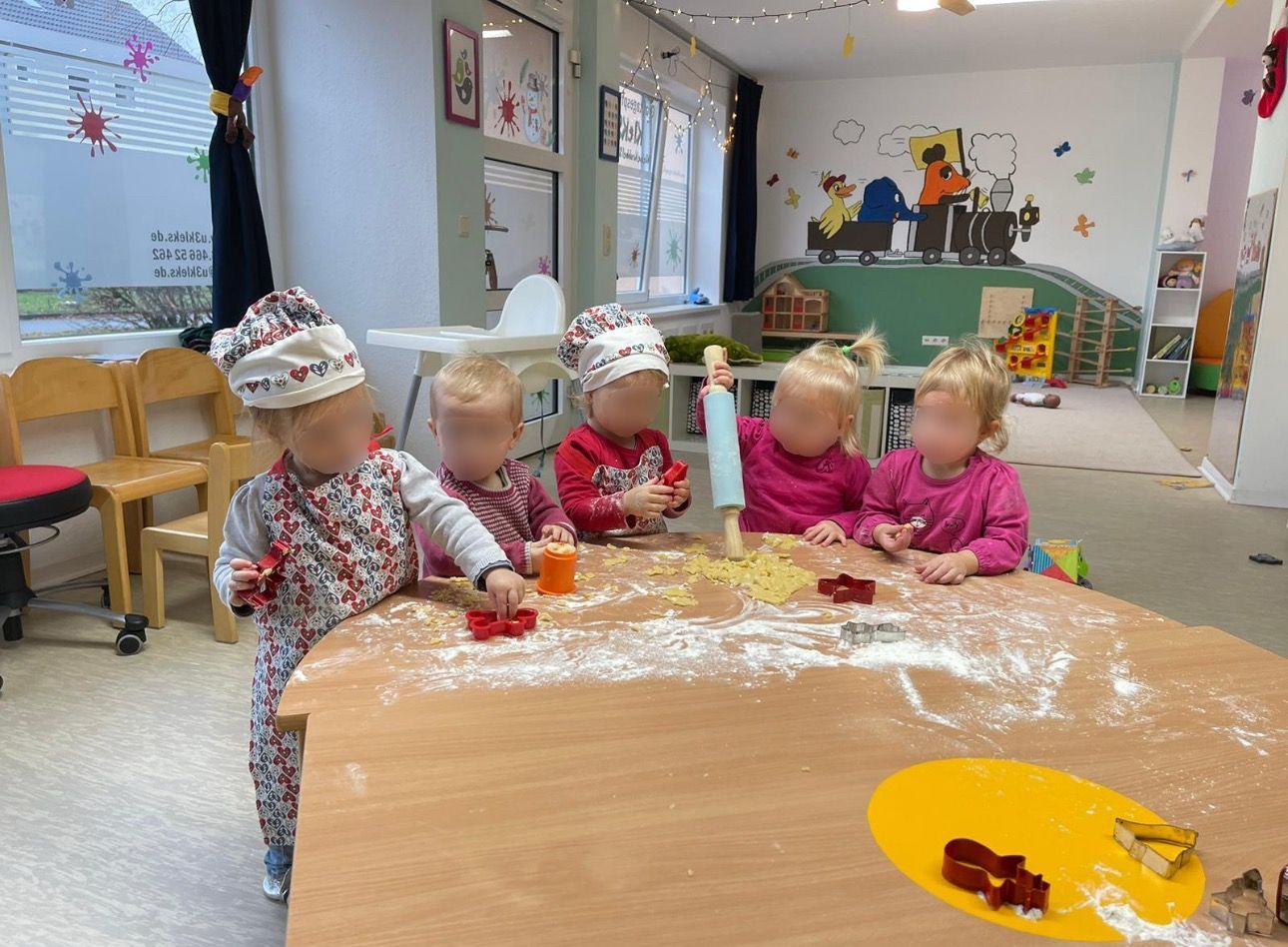 Eine Gruppe von Kindern sitzt in einem Raum um einen Tisch herum.
