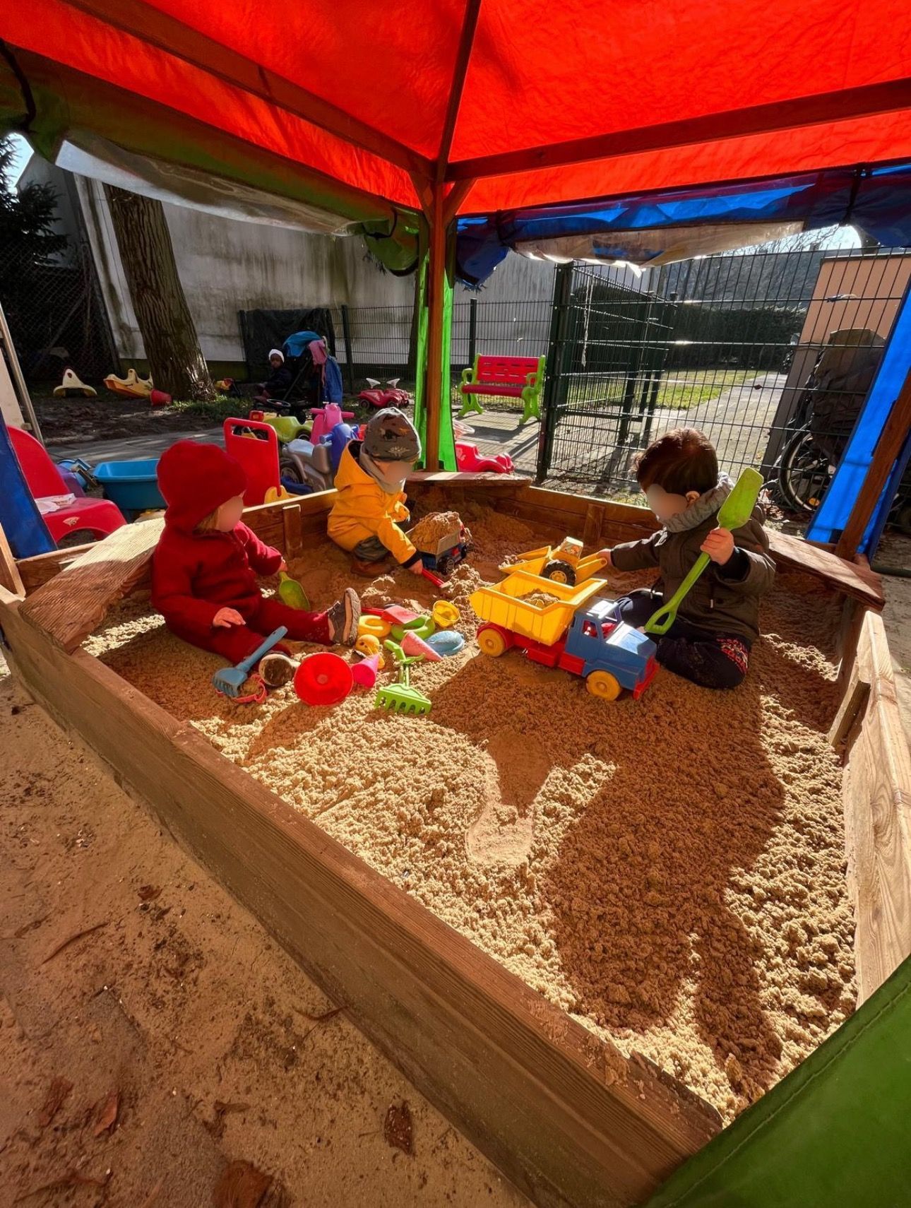 Eine Gruppe Kinder spielt in einem Sandkasten.