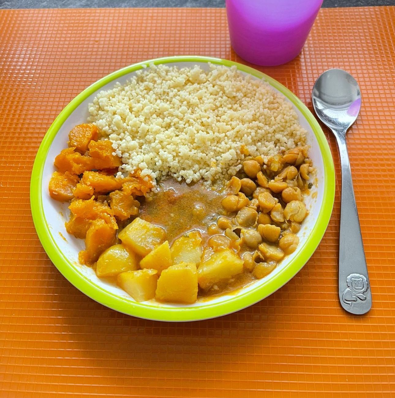 Ein Teller mit Essen mit Reis, Kartoffeln und Kichererbsen neben einem Löffel