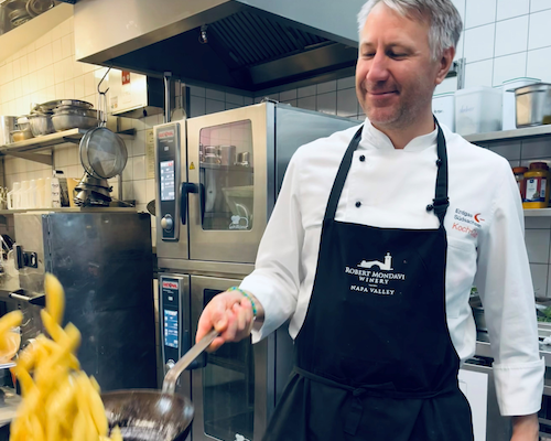 Ein Koch wirft Pommes frites in einer Pfanne in einer Restaurantküche.