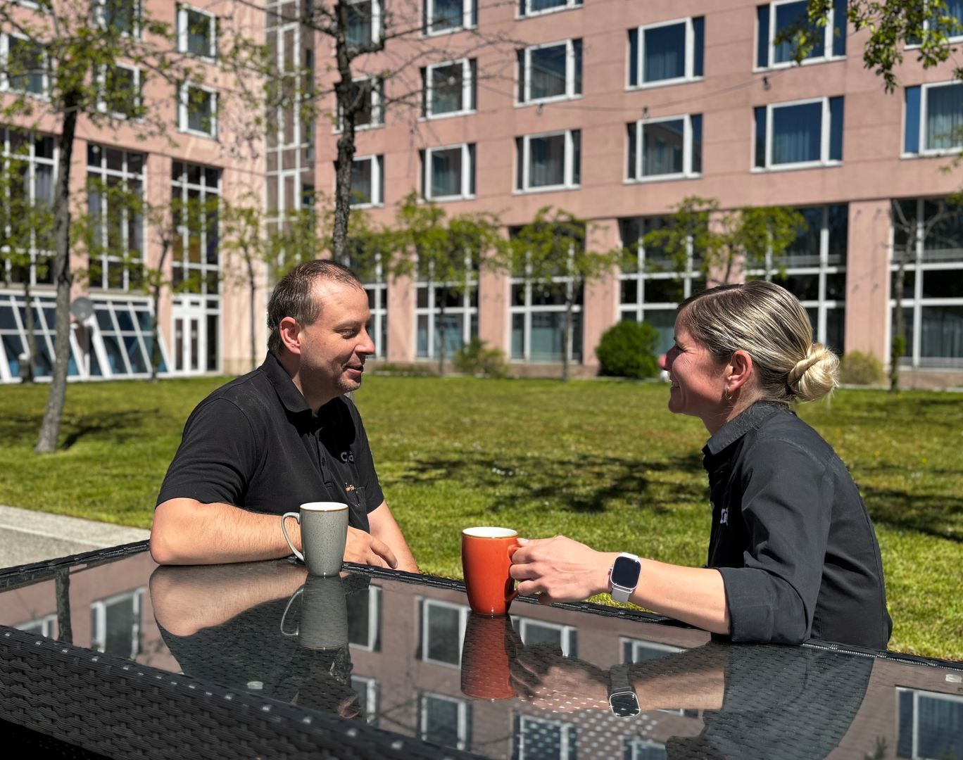 Zwei Personen unterhalten sich an einem Tisch im Hotelgarten des c/o56 Chemnitz mit Getränken.