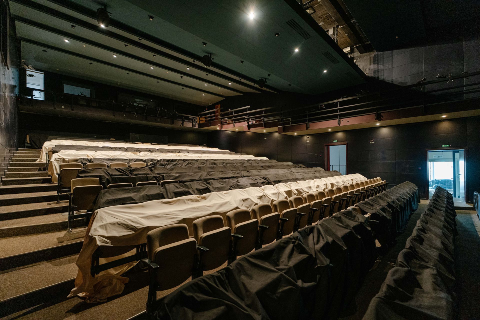 Leerer Theatersaal mit Reihen überdachter Sitze und gedämpfter Deckenbeleuchtung