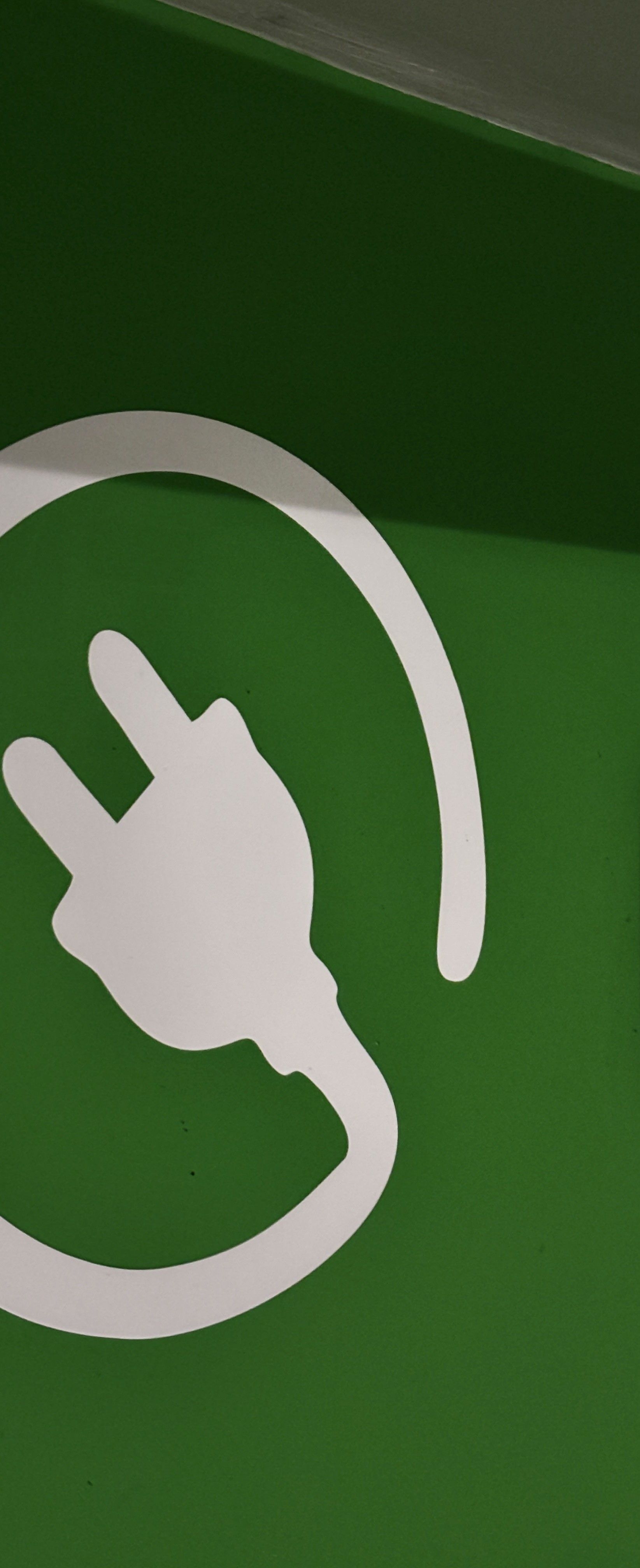 Weißes Steckersymbol auf grünem Hintergrund, teilweise beschnitten.