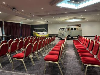 Konferenzraum im Tagungshotel Chemnitz mit Stuhlreihen und Auto im Hintergrund.