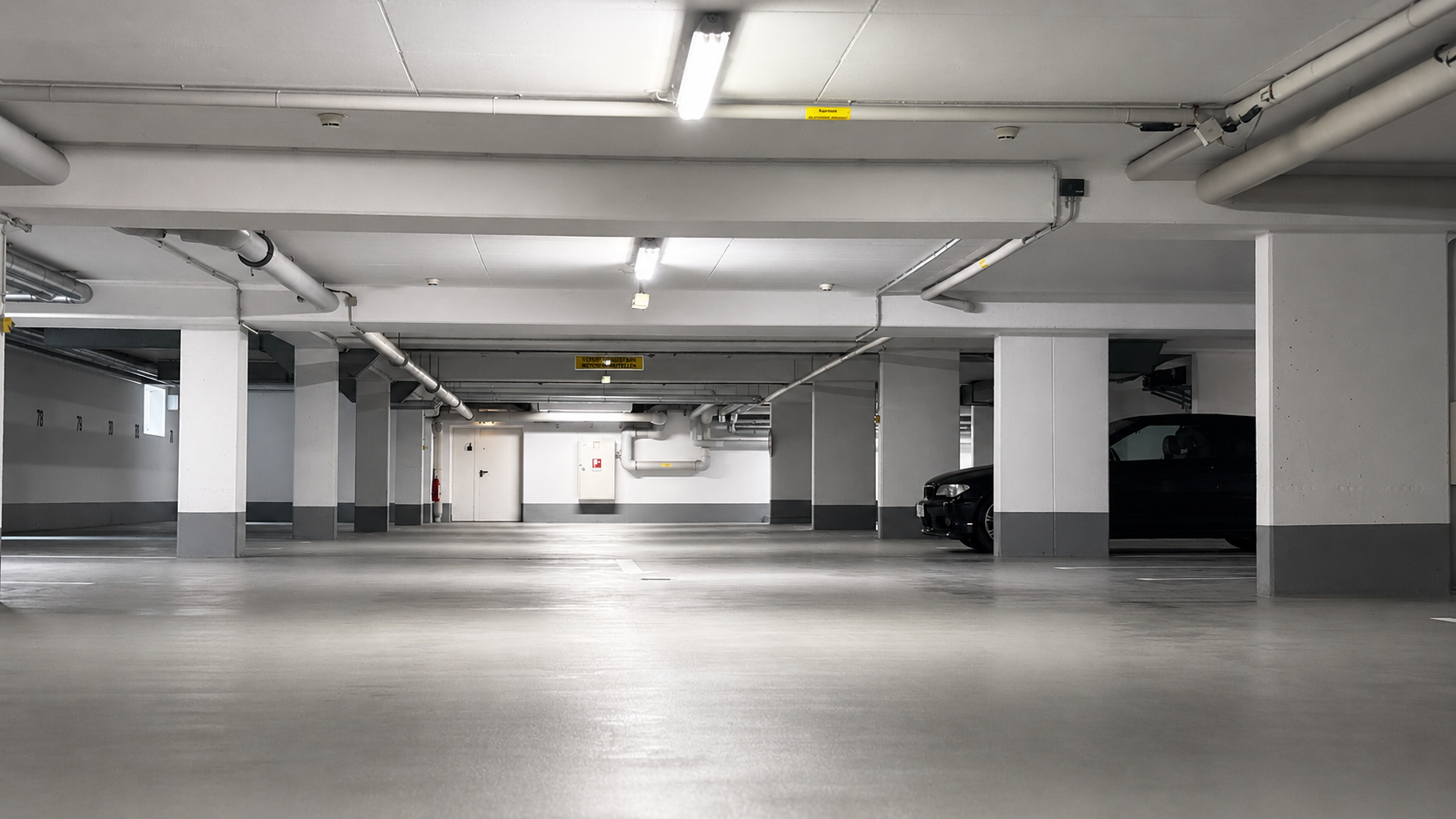 Zwei Elektroautos parken in einer leuchtend grünen Ladestation in einer Tiefgarage.