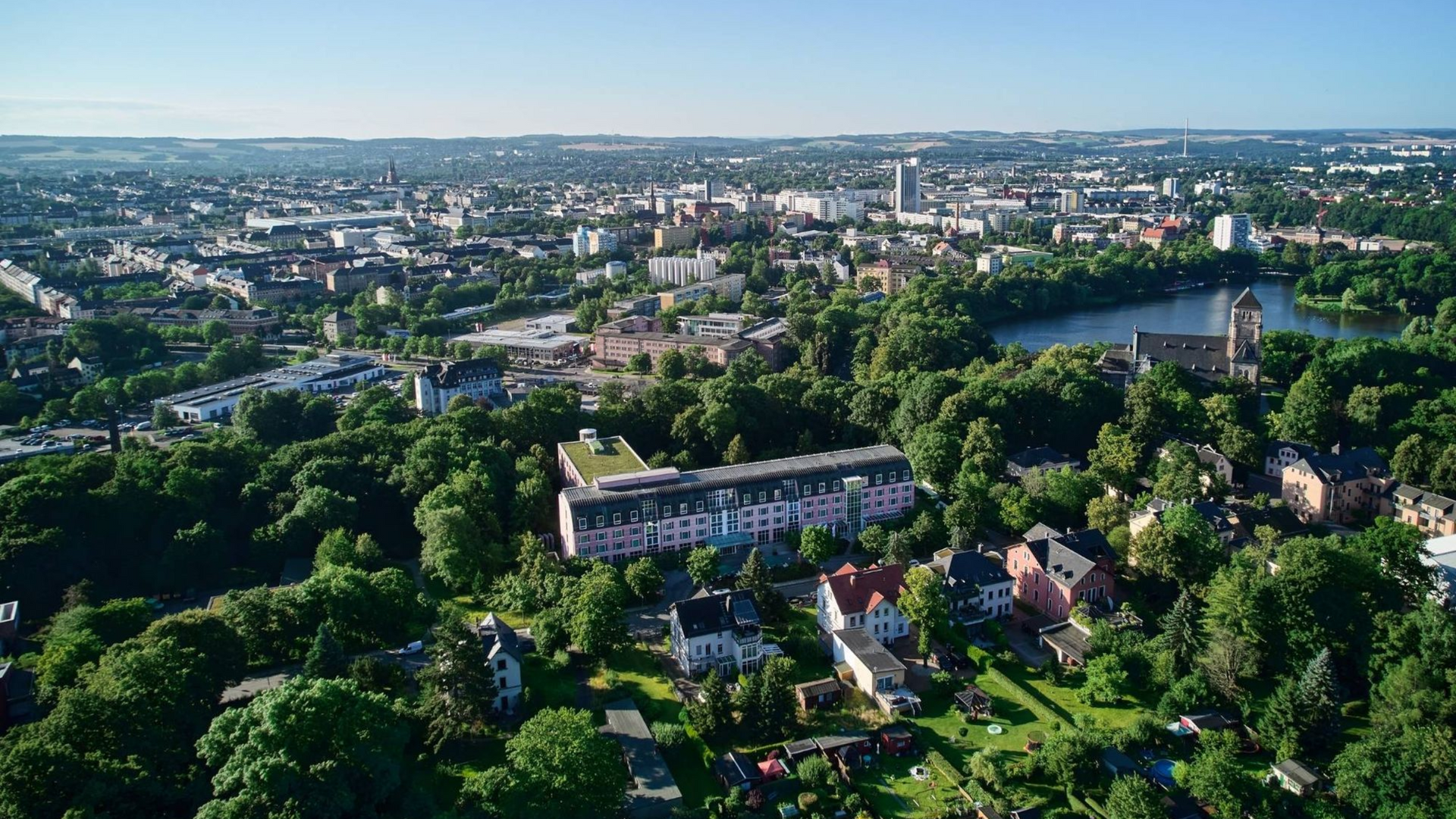 Luftaufnahme von Chemnitz mit Häusern, Bäumen und einer weitläufigen Skyline unter klarem Himmel