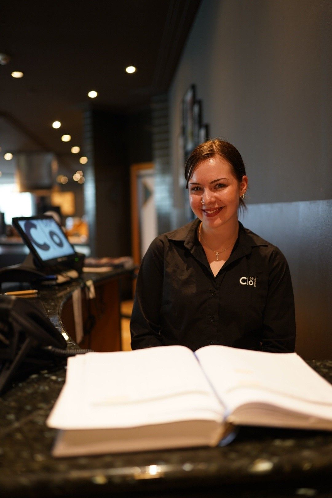 Eine Person sitzt auf einem Bett und schaut in eine Zeitschrift. Schallplatten, eine Kerze und ein Beistelltisch.