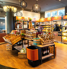 c/onsum56 Innenansicht eines Lebensmittelgeschäfts mit Holzregalen, Körben und verschiedenen Lebensmitteln zum Verkauf.