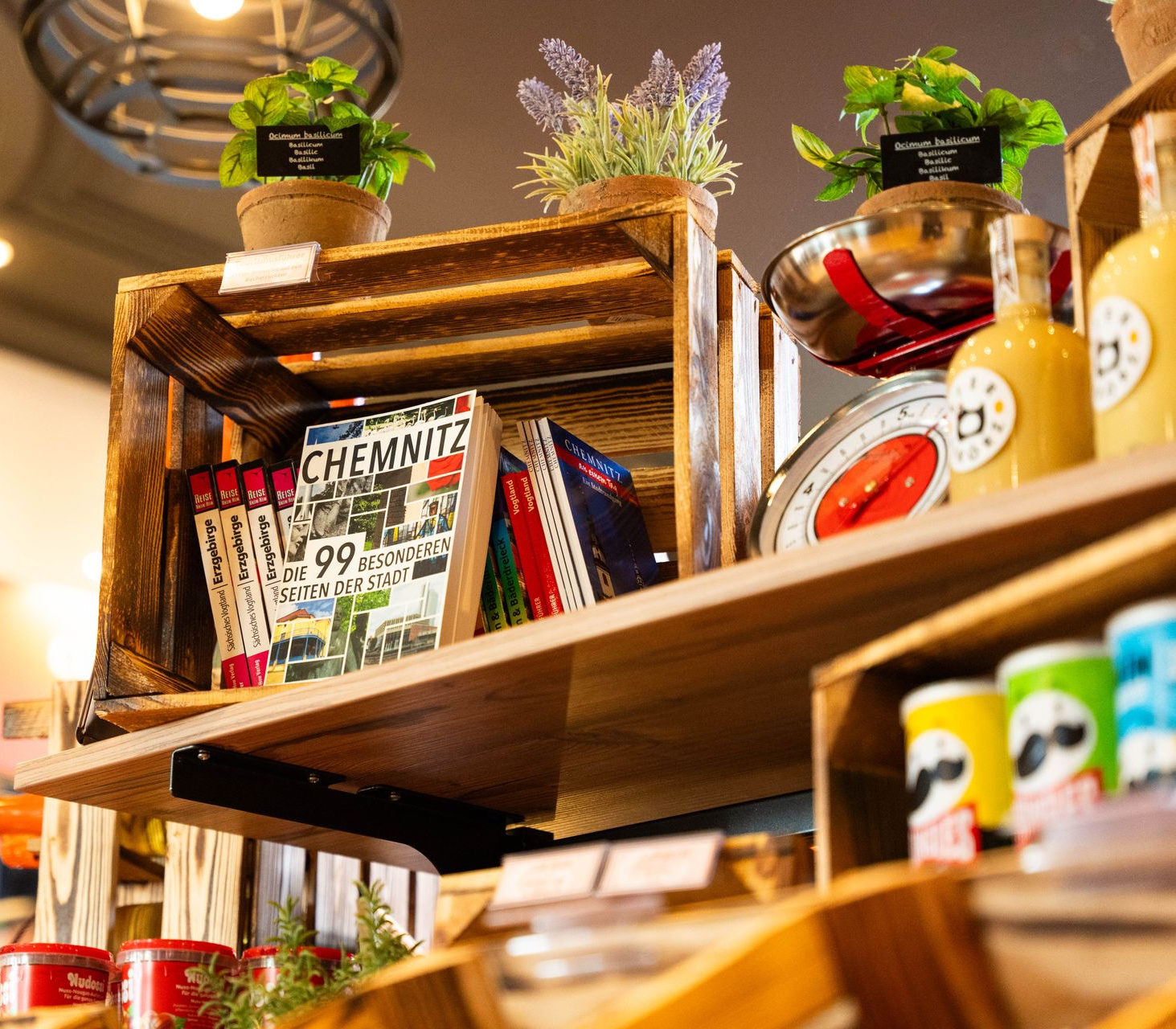 Holzregale mit Topfkräutern, Büchern und Einmachgläsern mit Lebensmitteln.