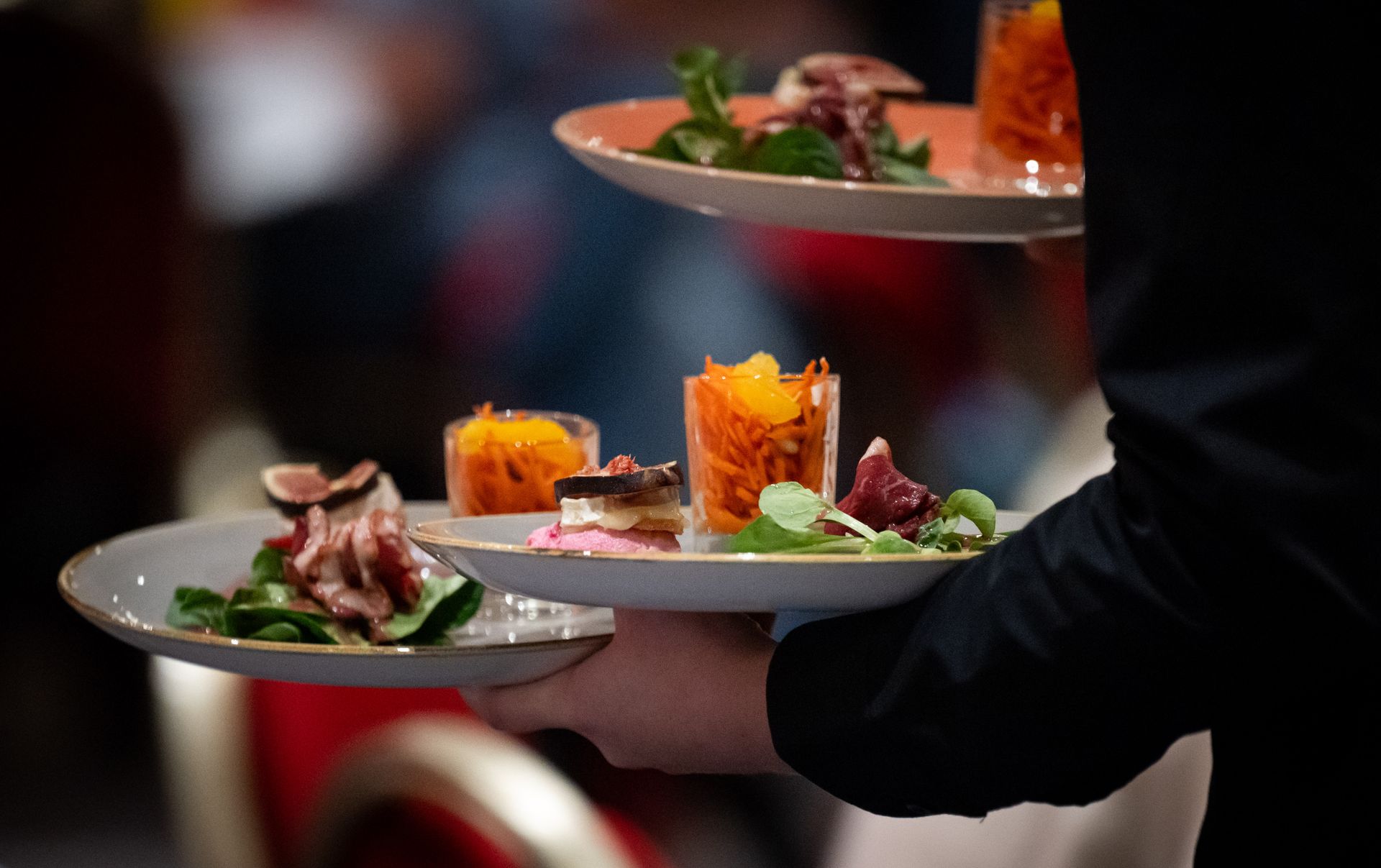Ein Kellner hält zwei Teller mit Vorspeisen.