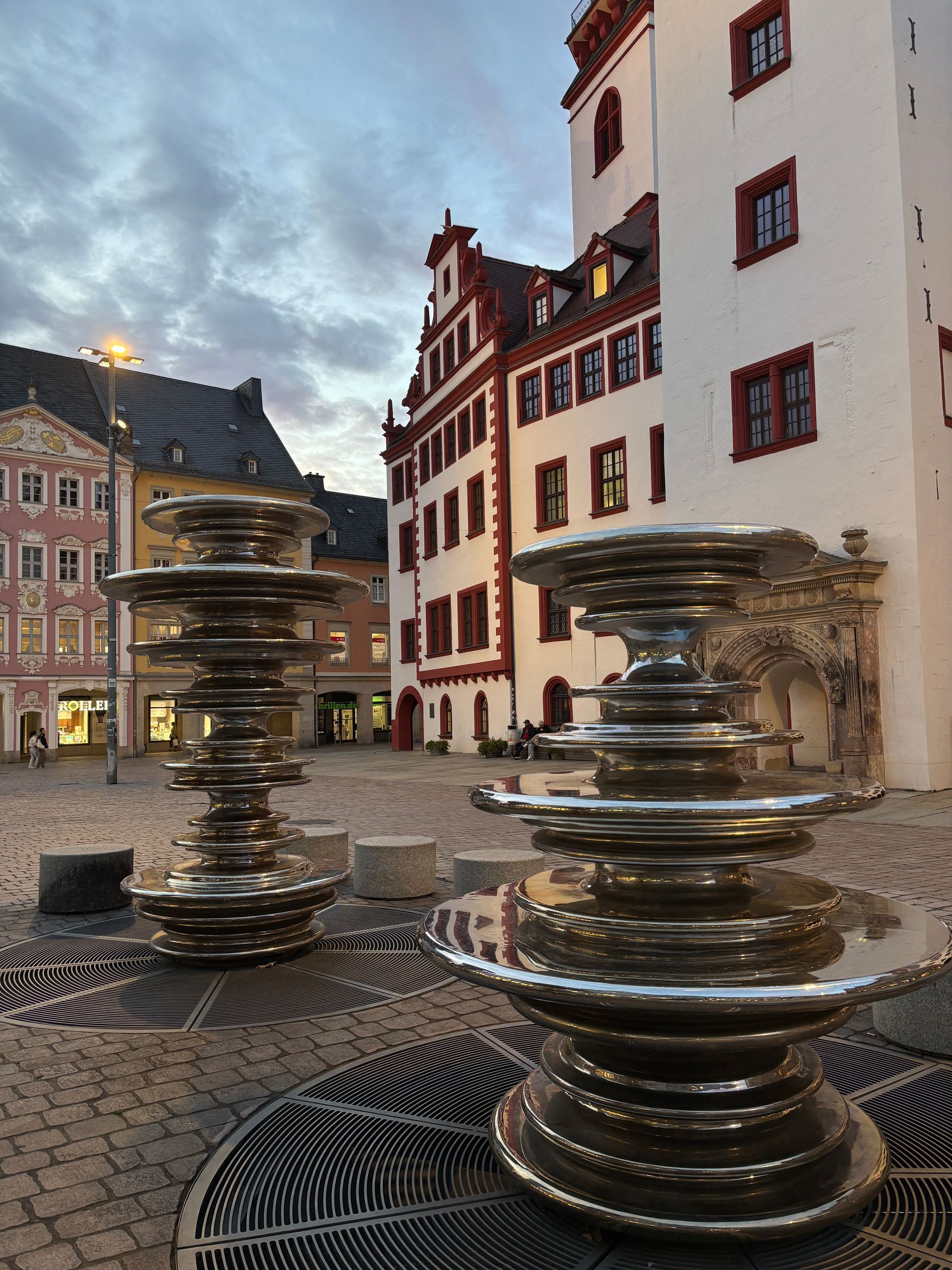 Eine Hand öffnet den Vorhang und gibt den Blick auf Bäume und Himmel frei.